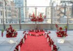Red carpet proposal pathway with LED pillar candles and red floral arrangements on a rooftop terrace overlooking the Manhattan skyline on a clear day