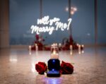 Close-up of 'Will You Marry Me' neon sign glowing in blue light surrounded by red roses and candles in an intimate indoor setting
